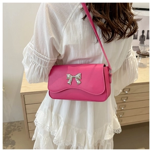 Detail view of pink shoulder bag with silver butterfly buckle on white lace dress