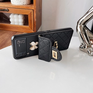 Detail of black quilted leather phone case with gold clover motif and folding wallet pouch