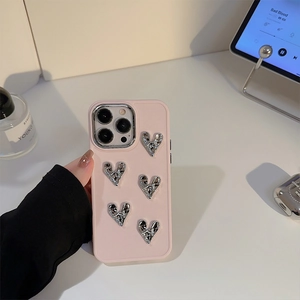 Pink iPhone case featuring five 3D silver metal hearts shown in a lifestyle setting