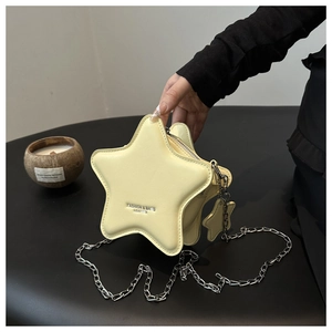 Detail of light yellow star-shaped leather crossbody bag with silver chain strap and pendant