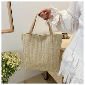 Detail of woven tote bag with beige herringbone texture and brown leather handles