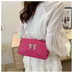 Detailed view of magenta shoulder bag featuring a silver bow buckle and chain strap