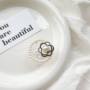 Close-up of camellia flower phone socket with pearls on a white ceramic plate