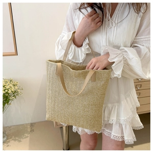 Detailed close-up of woven herringbone pattern and faux leather handles on summer tote bag
