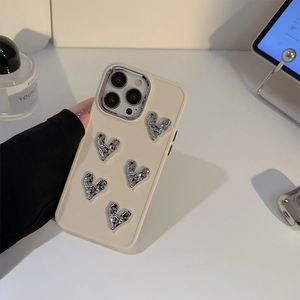Close-up of beige iPhone case featuring 3D silver hearts in a stylish lifestyle setting