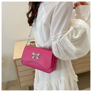 Detailed shot of hot pink crossbody bag featuring a silver butterfly buckle and chain strap