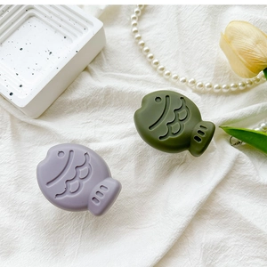 Detail of olive green and lavender 3D fish phone grip with matte finish on linen background
