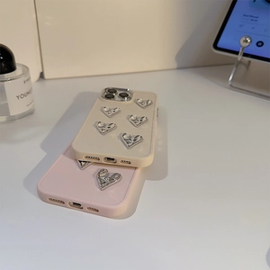 Close-up of pink and yellow iPhone cases with 3D silver hearts on a stylish desk