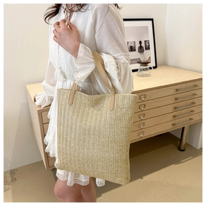 Detail of hand-woven straw tote bag with premium faux leather handles and herringbone texture