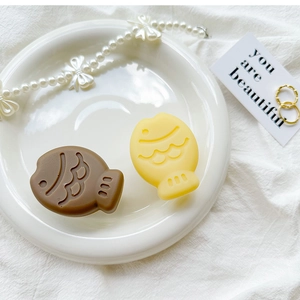 Detailed view of 3D silicone fish phone grips in brown and cream yellow on a white plate