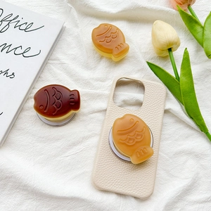 Matte fish-shaped expandable phone grip on beige leather case with aesthetic background