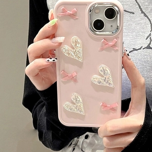 Close-up of pink iPhone case featuring 3D bow and iridescent heart decorative accents
