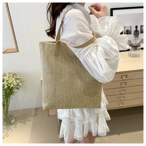 Detail of hand-woven straw tote bag with brown PU leather straps and V-shaped pattern