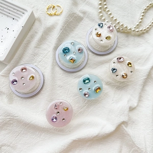Detail of glitter resin phone grips featuring colorful rhinestones on a soft fabric