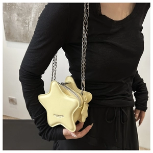 Detail of yellow star-shaped crossbody bag with chain strap worn by a model