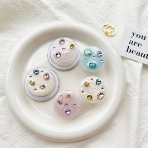 Detail of assorted rhinestone-encrusted phone grip stands on a white decorative tray
