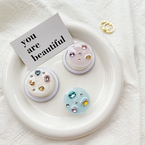 Close-up of pastel resin phone sockets with sparkling crystals in a ceramic tray