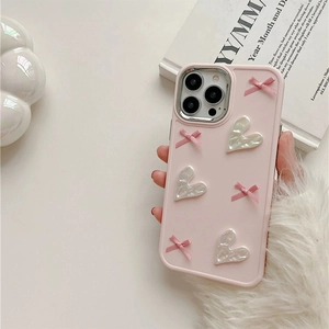 Detail of pink iPhone case featuring white shell hearts and 3D ribbon bows decoration