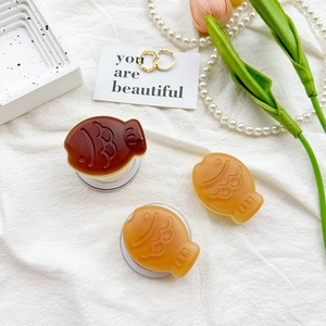 Close-up of matte fish-shaped phone grips on white fabric with elegant jewelry accents