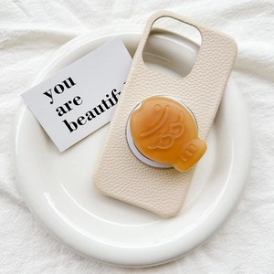 Litchi pattern cream phone case with 3D brown fish pop socket on white ceramic plate