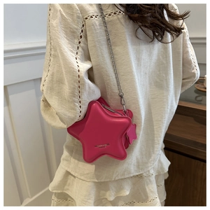 Close-up of a pink star-shaped crossbody bag with silver chain on a white dress