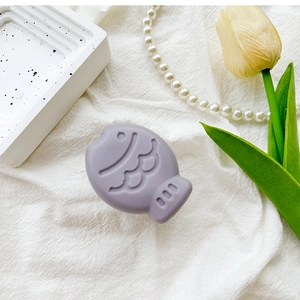 Detailed view of the purple fish-shaped silicone phone stand on a decorative tray