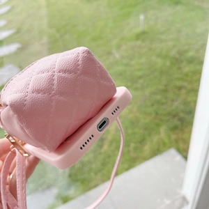 Detail of pink quilted mini bag phone case with adjustable crossbody strap on grass