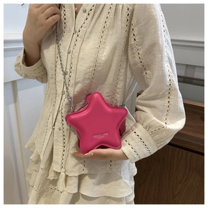 Close-up of pink star-shaped crossbody bag with silver chain strap on a model