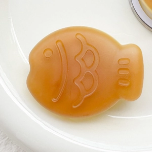 Detail showing translucent orange matte fish phone grip on white ceramic plate