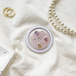 Detail of pink glitter phone socket with colorful rhinestones on textured fabric