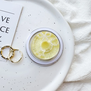 Close-up of a yellow eyelash case with pearl bow decor on a decorative white plate