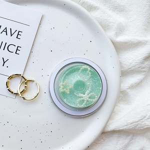 Detail of light green pearl donut phone grip with gold rings on a ceramic plate