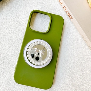 Close-up of green phone case featuring a mirrored bow and pearl socket grip stand