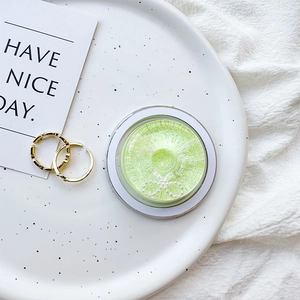 Macro shot of two gold rings and a green storage box with a pearl bow on a ceramic plate