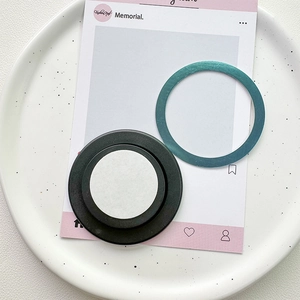 Detail of magnetic phone socket base with teal metallic ring on a decorative tray