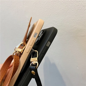 Détail d'une coque en silicone avec bandoulière en cuir et boucles dorées