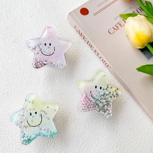 Star-shaped glitter phone sockets with sequins, pearls and smiling faces on white surface