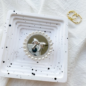 Detail of mirror phone grip with white faux pearls and a silver ribbon bow ornament