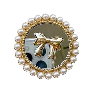 Chic phone grip featuring a reflective mirror with golden bow and pearl ring frame