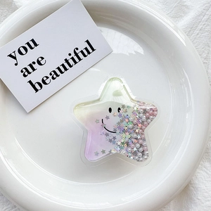 Star-shaped phone grip with glitter, pearls, and smile face on a ceramic plate