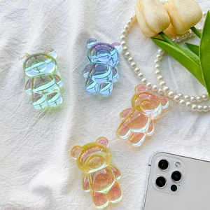 Iridescent bear phone grip holders in pastel colors on white fabric with tulips