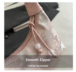 Detail of smooth metal zipper and floral jacquard texture on pink silk handbag