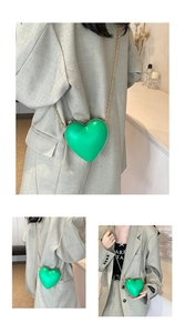 Close-up of bright green heart-shaped crossbody bag with gold chain strap detail