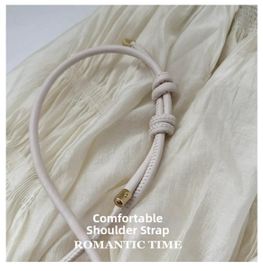 Close-up of beige leather strap with knot design and gold metal cylindrical end caps