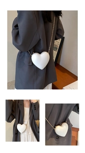 Detail of a white heart-shaped crossbody bag with gold chain strap for women