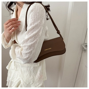 Detail of dark brown leather underarm bag with gold logo and stylish knotted strap
