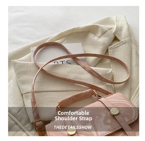 Détail du sac bandoulière rose à texture marbrée posé sur un blazer beige texturé