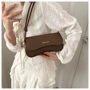 Detail of dark brown leather underarm bag with knot strap and gold fashion logo
