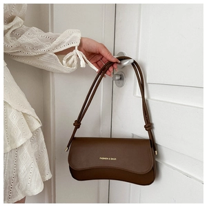 Close-up of a dark brown leather underarm bag with knot details and fashion logo