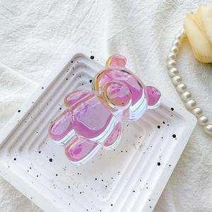 Macro detail of cute holographic laser pink bear phone socket on a marble tray background